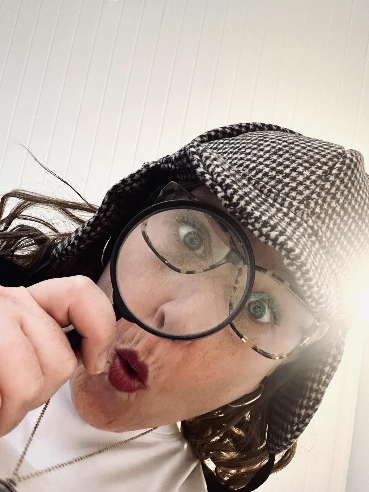 Sarah in a deerstalker hat, peering through a magnifying glass